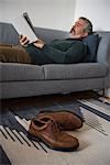 Man reading book in living room at home