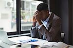 Stressed businessman sitting at his desk in office