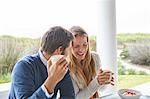 Laughing couple drinking coffee on patio