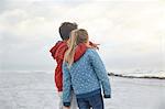 Affectionate brother and sister looking at winter ocean