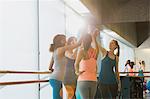 Women high fiving in sunny gym studio