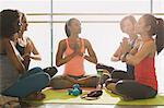 Serene women meditating in yoga class gym studio