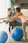 Woman tying shoe at barre in exercise class gym studio