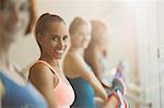 Portrait smiling women stretching legs at barre in exercise class gym studio