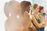 Serene women practicing yoga with hands at heart center in gym studio