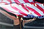 Female athlete running victory lap with American flag