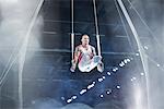 Focused male gymnast performing on gymnastics rings in arena