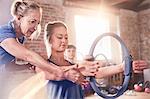 Fitness instructor helping young woman using pilates ring in exercise class gym studio