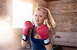 Portrait tough young woman boxing in studio