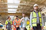 Steel workers talking and walking on coffee break in factory