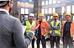 Steel workers listening to manager in meeting in factory