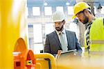 Manager and steel worker examining equipment in factory