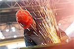 Welder using welding torch with sparks in steel factory