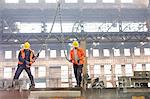 Steel workers with crane hooks in factory