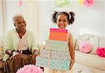 Portrait smiling girl carrying stack of birthday gifts