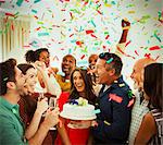 Enthusiastic family with birthday cake throwing confetti