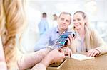 Couple paying for jewelry watching jeweler using credit card reader