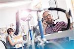 Bicycle leaning against desk next to male design professional talking on cell phone in office