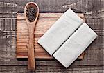 Pepper on spoon and kitchen towel on wooden board. Place for text