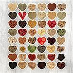 Aphrodisiac food for sexual health in heart shaped bowls over distressed white wood background.