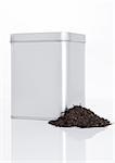 Black tea steel jar with loose tea next to it on white background