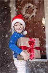 little boy in santa's hat holding christmas gift enjoying snowy christmas time