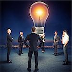 Team of businesspeople watch a big lightbulb