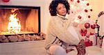 Beautiful african american woman with big afro haircut  seated next to fireplace and white christmas tree with presents under it