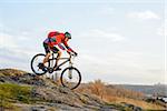 Cyclist in Red Jacket Riding the Bike Down Rocky Hill. Extreme Sport Concept. Space for Text.