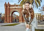 in Barcelona for a perfect winter. Portrait of happy elegant woman in earmuffs in Barcelona, Spain standing near Arc de Triom