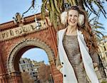 in Barcelona for a perfect winter. happy young fashion-monger in earmuffs near Arc de Triomf in Barcelona, Spain