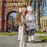 in Barcelona for a perfect winter. happy young mother and child near Arc de Triomf in Barcelona, Spain looking at the map