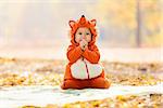 Cute baby boy dressed in fox costume in autumn park