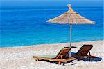 Summer morning sandy beach with sunbeds and strawy sunshade (Albania).