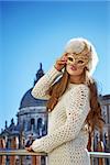 Another world vacation. Portrait of elegant fashion-monger in fur hat in Venice, Italy wearing Venetian mask