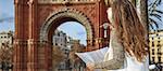 in Barcelona for a perfect winter. Seen from behind elegant woman in earmuffs near Arc de Triomf in Barcelona, Spain looking at the map