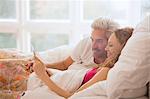 Couple relaxing laying in bed using digital tablet