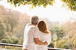 Affectionate couple hugging looking at autumn trees on patio