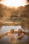 Serene affectionate couple soaking in hot tub on patio with autumn view