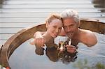 Portrait affectionate couple drinking champagne soaking in hot tub on patio