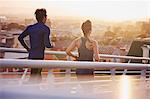 Runner couple running on footbridge with city view