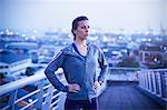 Determined female runner resting on urban footbridge at dawn