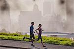 Runner couple running on sunny urban city sidewalk