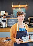 Portrait confident female cafe owner holding tray of coffee cups