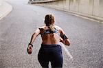 Fit female runner with mp3 player armband running on urban street