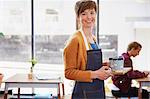 Portrait confident female cafe owner serving coffee on tray in cafe