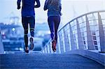 Runner couple running on urban footbridge at dawn