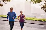 Runner couple running on sunny urban city street