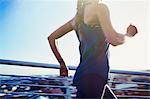 Female runner running on sunny urban footbridge