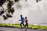 Runner couple running on sunny urban city street